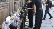 Policiais observam os tributos às vítimas do show do ataque terrorista ocorrido no show da cantora Ariana Grande em Manchester, na Inglaterra, em 23 de maio de 2017. As homenagens foram colocadas na praça St. Ann. 
 - AP