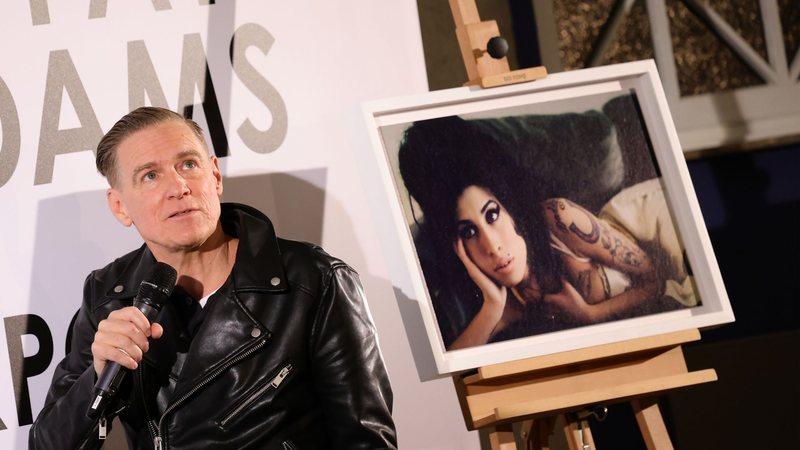 Bryan Adams ao lado de foto de Amy Winehouse (Foto: Andreas Rentz/Getty Images)