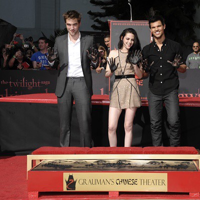 Robert Pattinson, Taylor Lautner e Kristen Stewart posam com as mãos sujas após deixarem suas impressões na Calçada da Fama