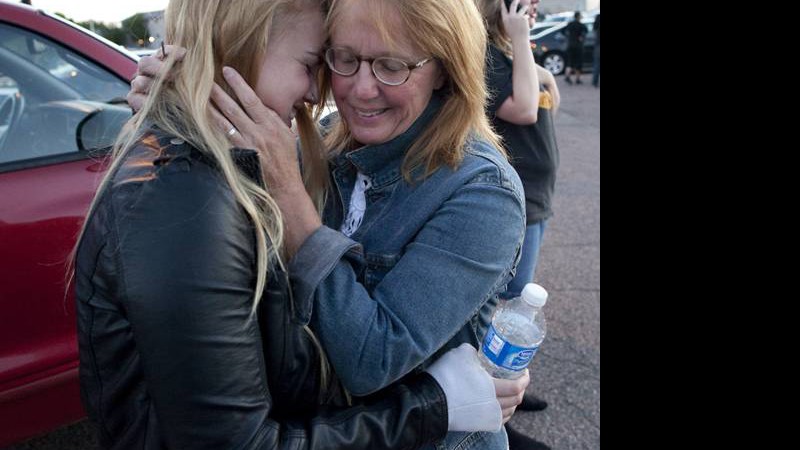 Emma Goos, 19, abraça a mãe, Judy Goos, do lado de fora da Gateway High School, onde testemunhas dão depoimentos sobre o crime. Emma estava na terceira fileira do cinema no qual o atirador matou 12 pessoas. Ela ajudou um homem que foi ferido 

