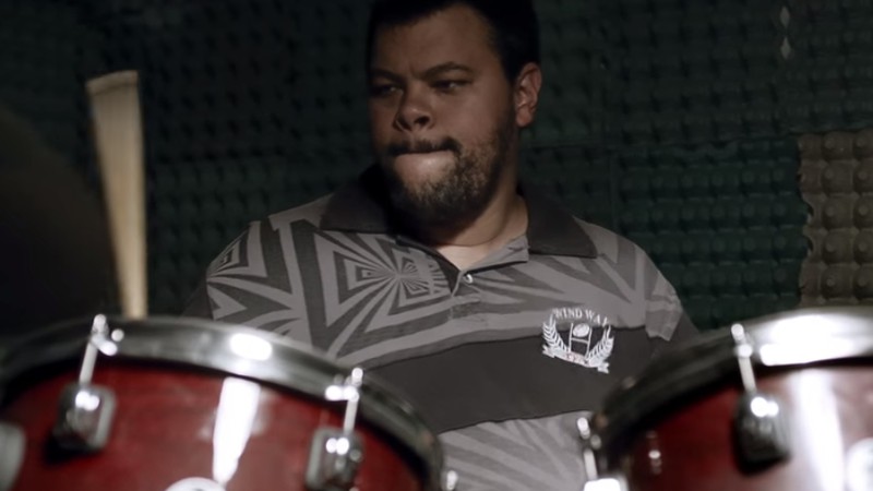 O ator Babu Santana dando vida ao personagem Santana enquanto ele toca bateria em cena do filme <i>Mundo Cão</i>, do diretor Marcos Jorge - Reprodução/Vídeo