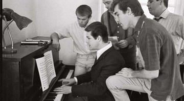 Em foto de 1964, Brian Wilson (ao piano) mostra uma nova composição para a banda. Junto a ele estão (da esq. para a dir.) Al Jardine, Mike Love, Dennis Wilson e Carl Wilson. - Divulgação
