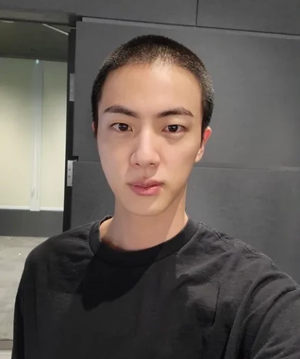 Jin, do BTS, com corte de cabelo militar em selfie