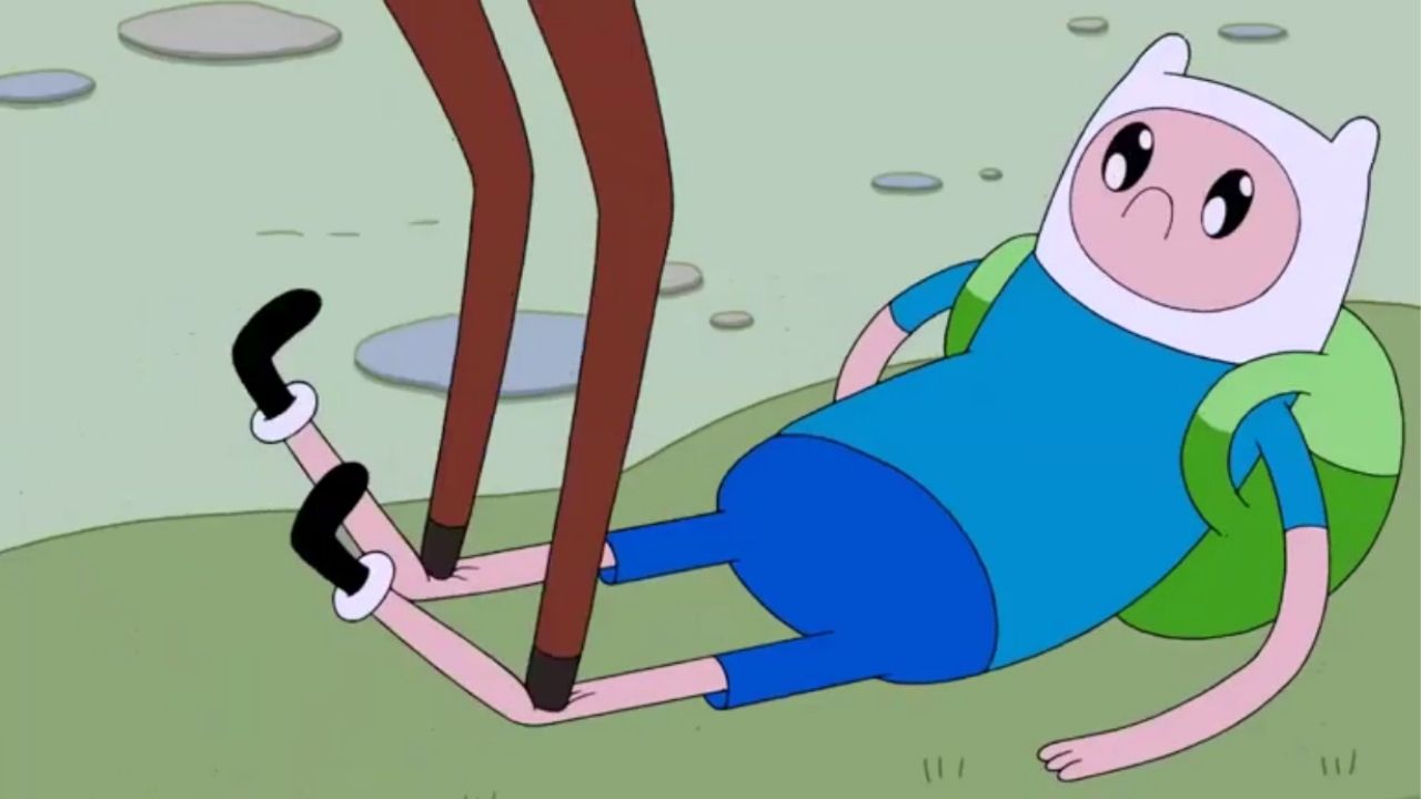 Finn deitado com os olhos arregalados. Duas pernas do alce estão em cima das pernas do humano.
